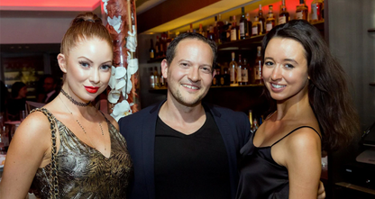 Elite Seduction Mastery client Adam success story - confident man with attractive women at upscale venue