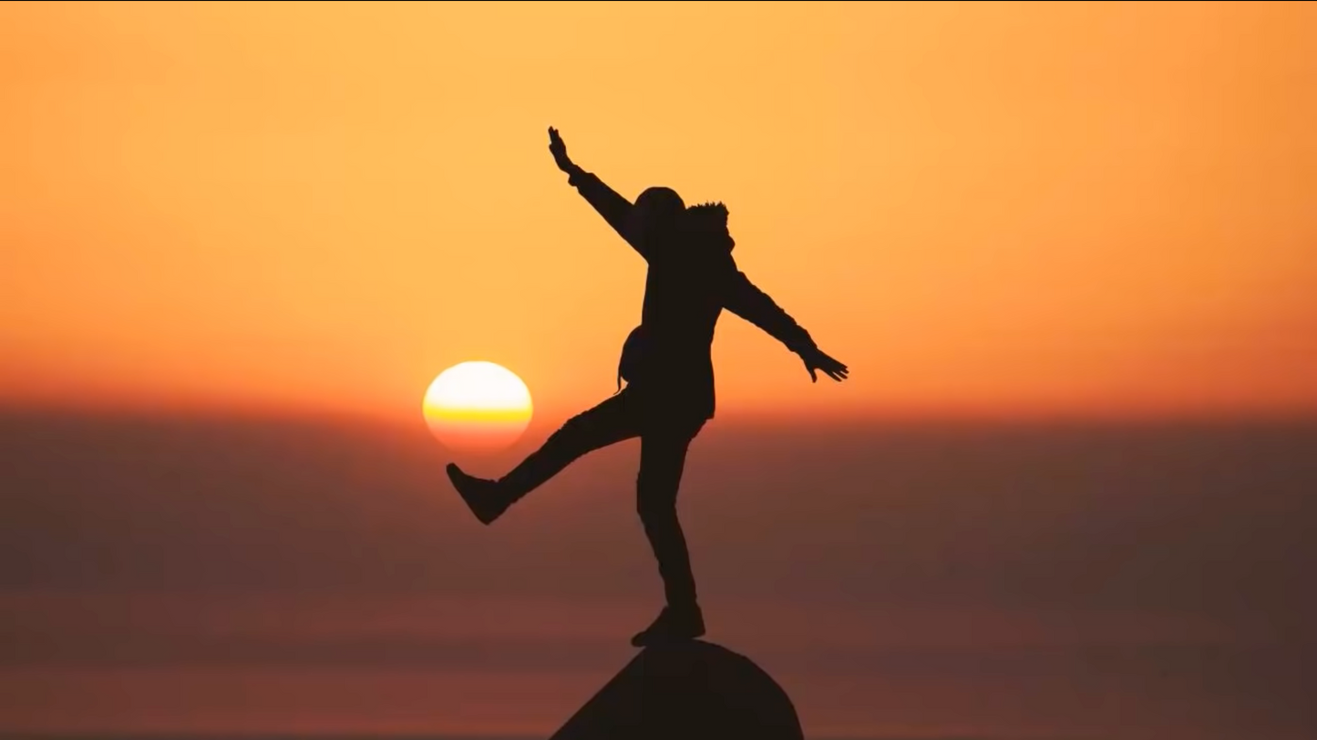 Life Coaching | Unlock your Potential Unleash your Power | Man Standing on a Rock with One Foot up With the Sun Setting on his foot like a soccer ball with an orange dusk back ground!