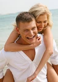 Broken to Bulletproof women's coaching - happy couple with blonde woman playfully embracing man at beach ocean setting